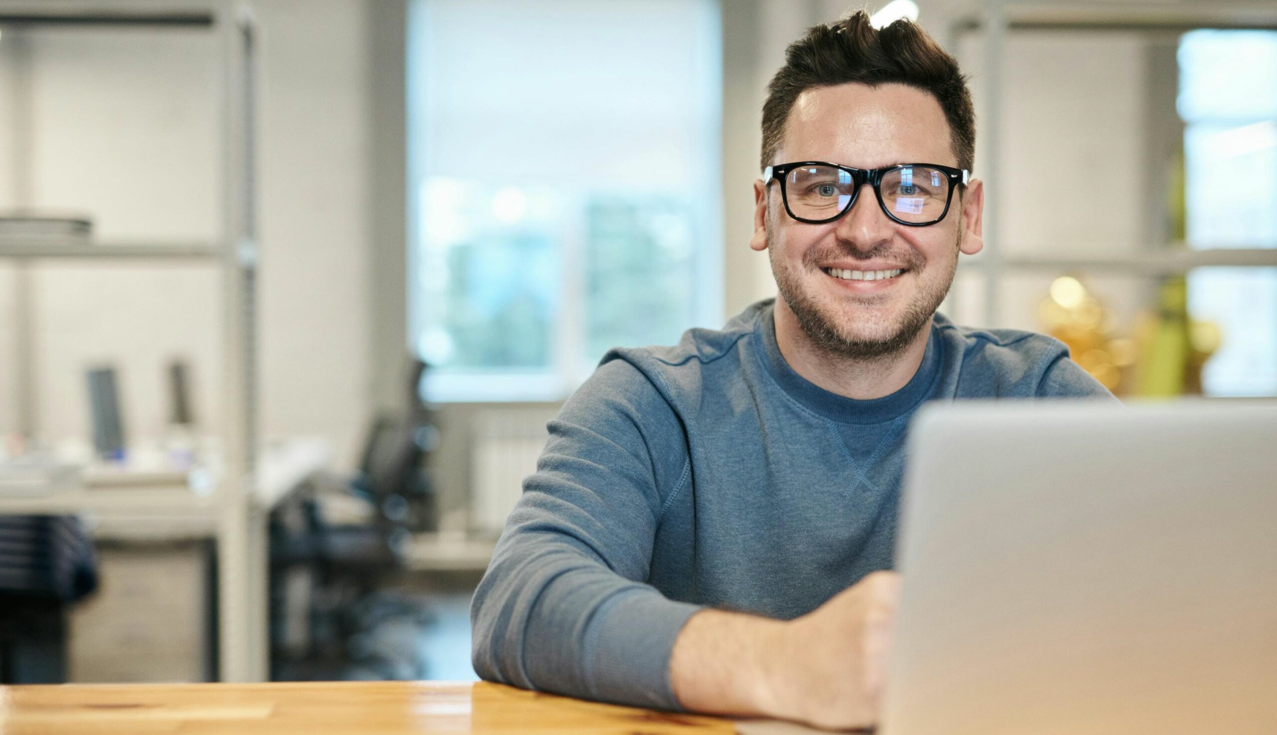 Smiling man with glasses with a laptop