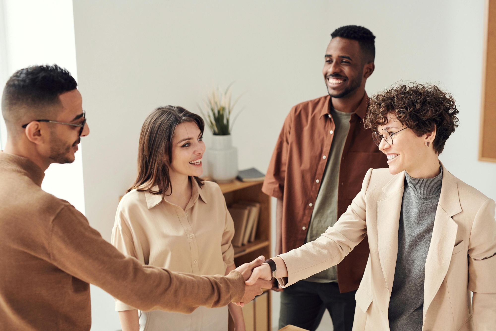 diverse group of professionals looking at each other, two shaking hands and smiling