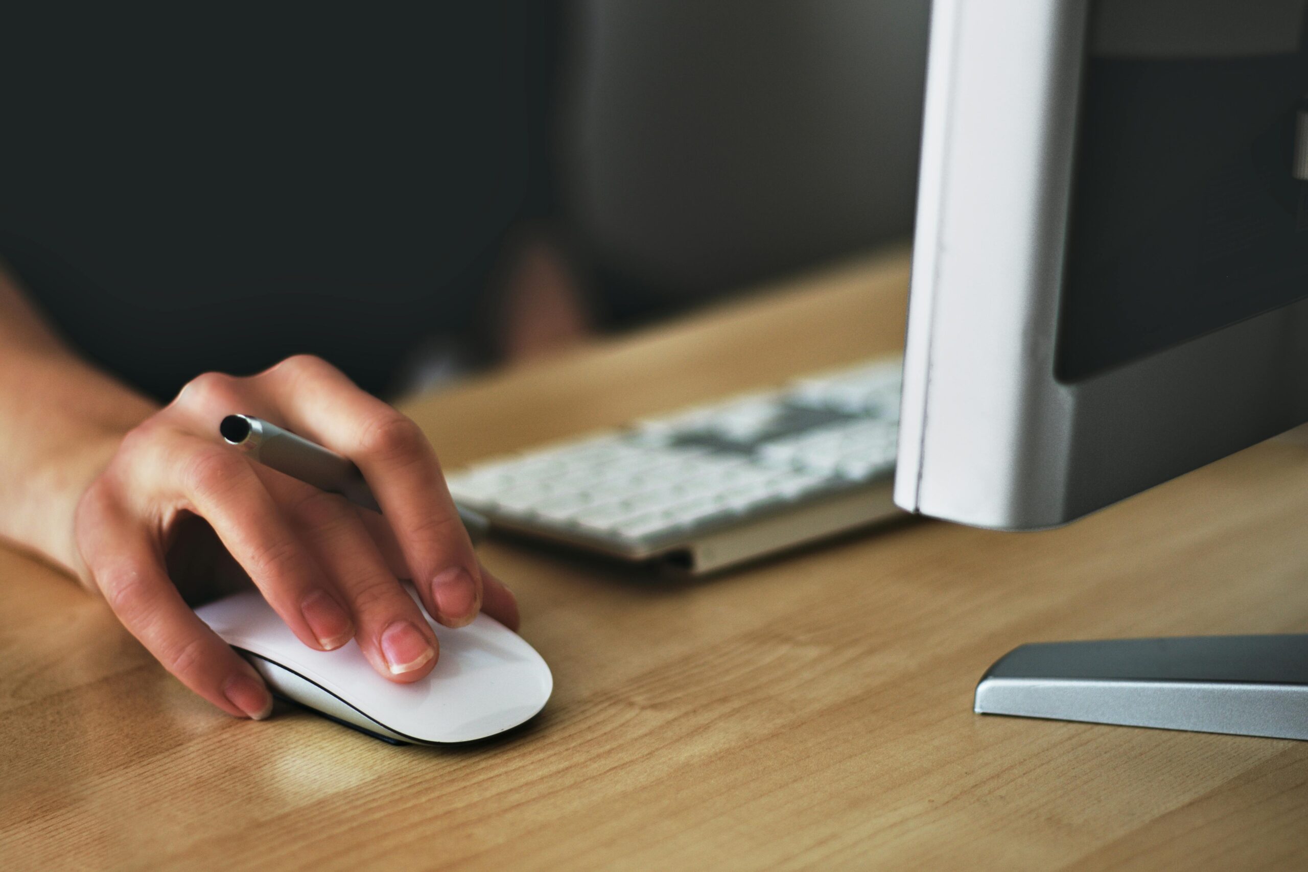 close up of a woman's hand on a mouse with the edge of a computer on the side