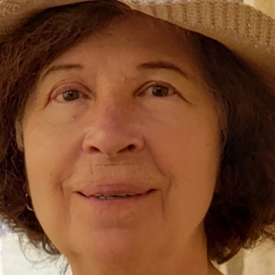 Older white woman with brown hair wearing a straw sunhat
